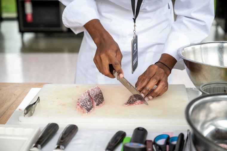A chef’s hands fillet fish on the cutting board.