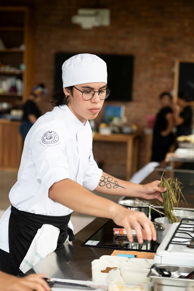 A contestant arranges fresh herbs next to the burners.