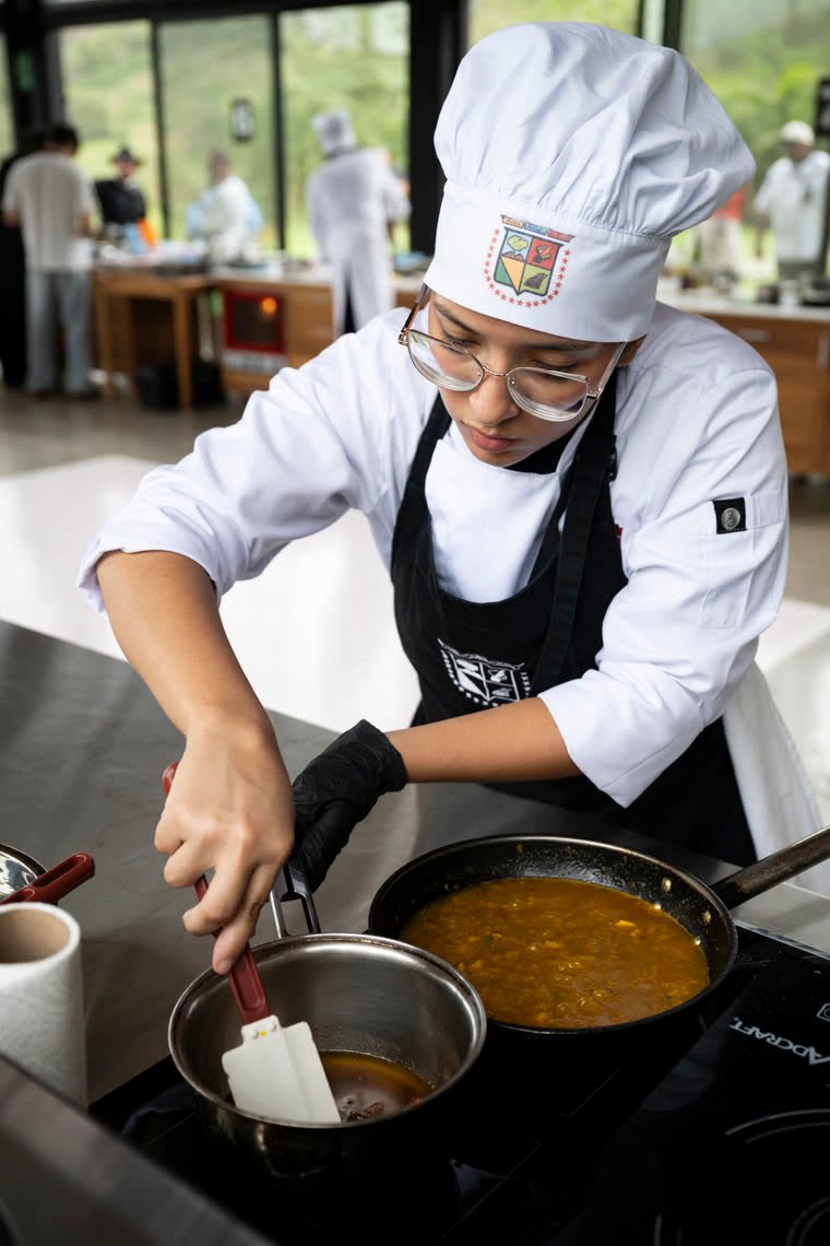 A contestant folds a sauce with a spatula.