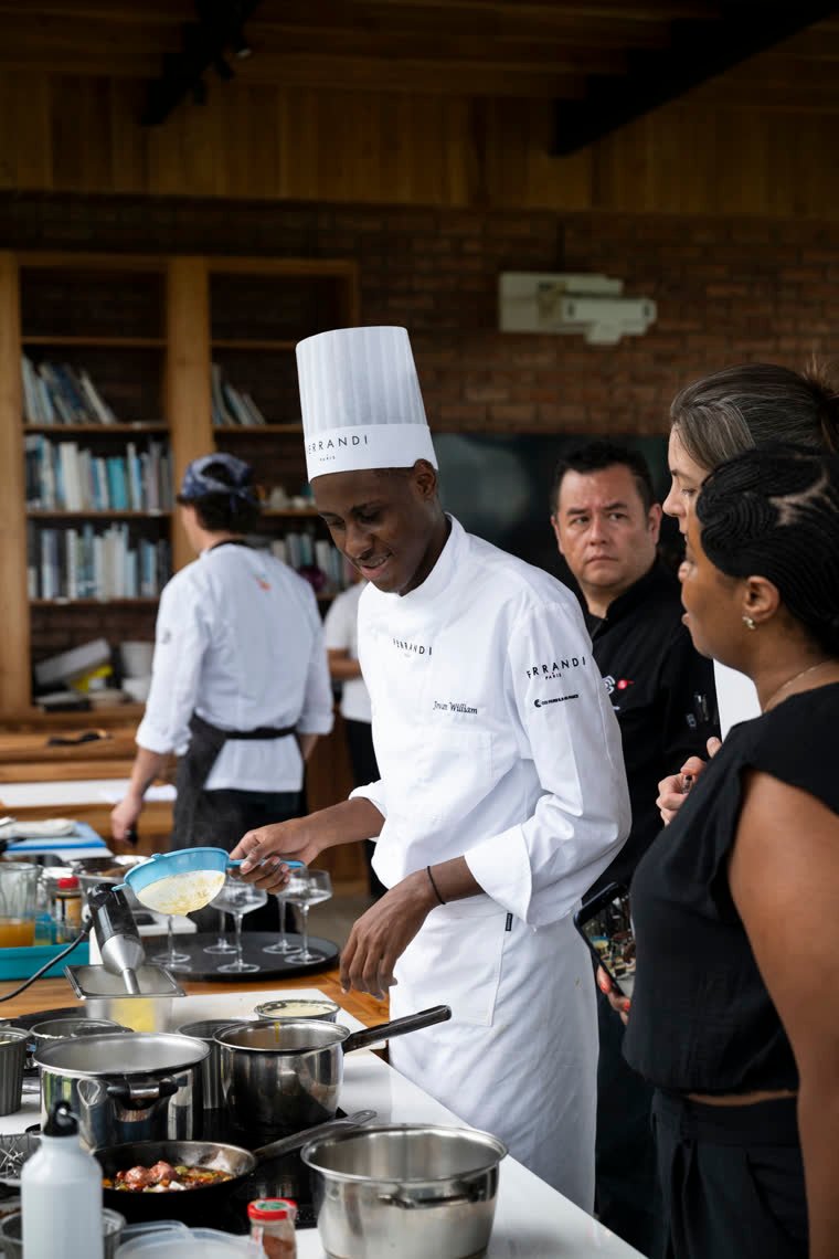 A contestant pours a preparation while the jury watches from behind.