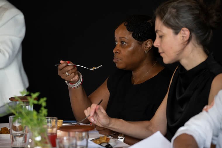 Two judges taste the dish with cutlery during the evaluation.