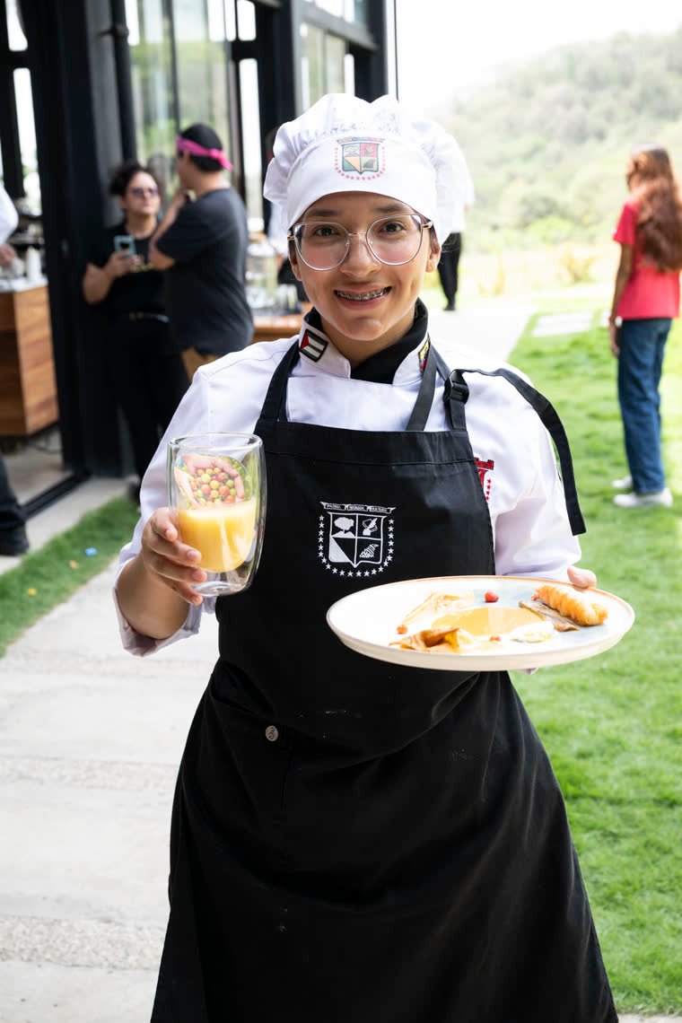 A contestant smiles holding her dish and a glass with a drink.