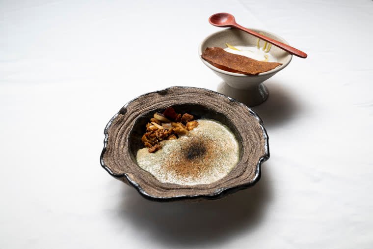 Two preparations in handmade ceramics on a white tablecloth.