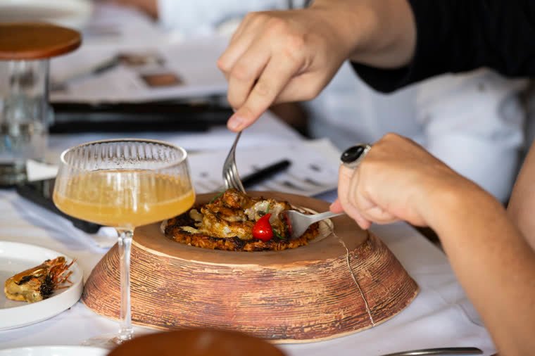 During the evaluation, a fork reaches the dish served on its ceramic base.