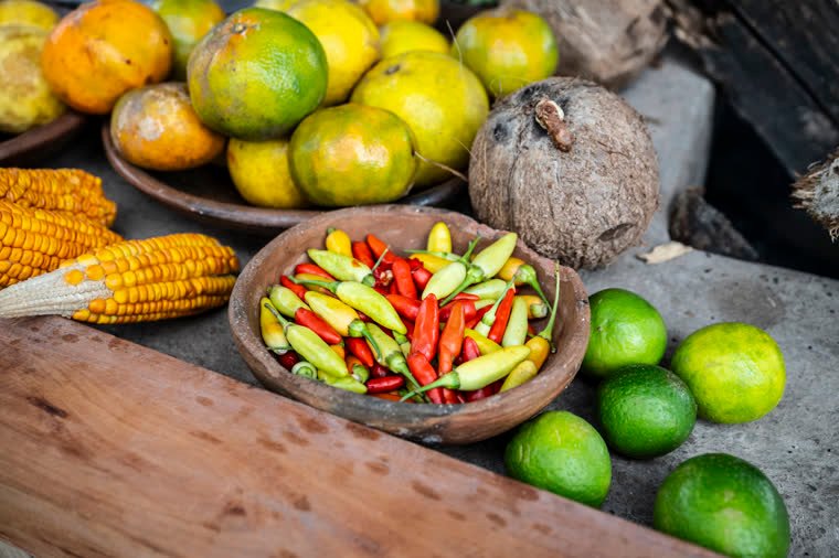 Oranges, chili peppers, corn, lemons and coconut on a rustic table.