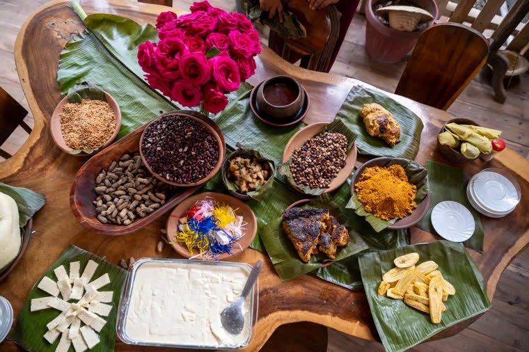 Table of local products served on banana leaves, with roses in the background.