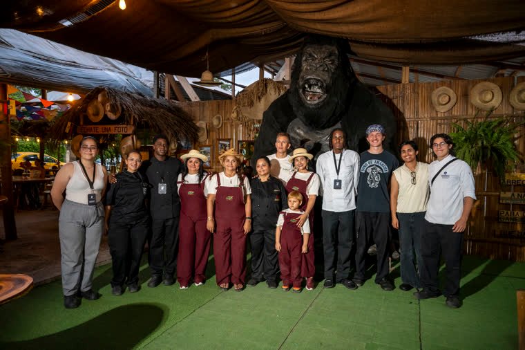 Group photo of participants and the restaurant team in front of a gorilla sculpture.